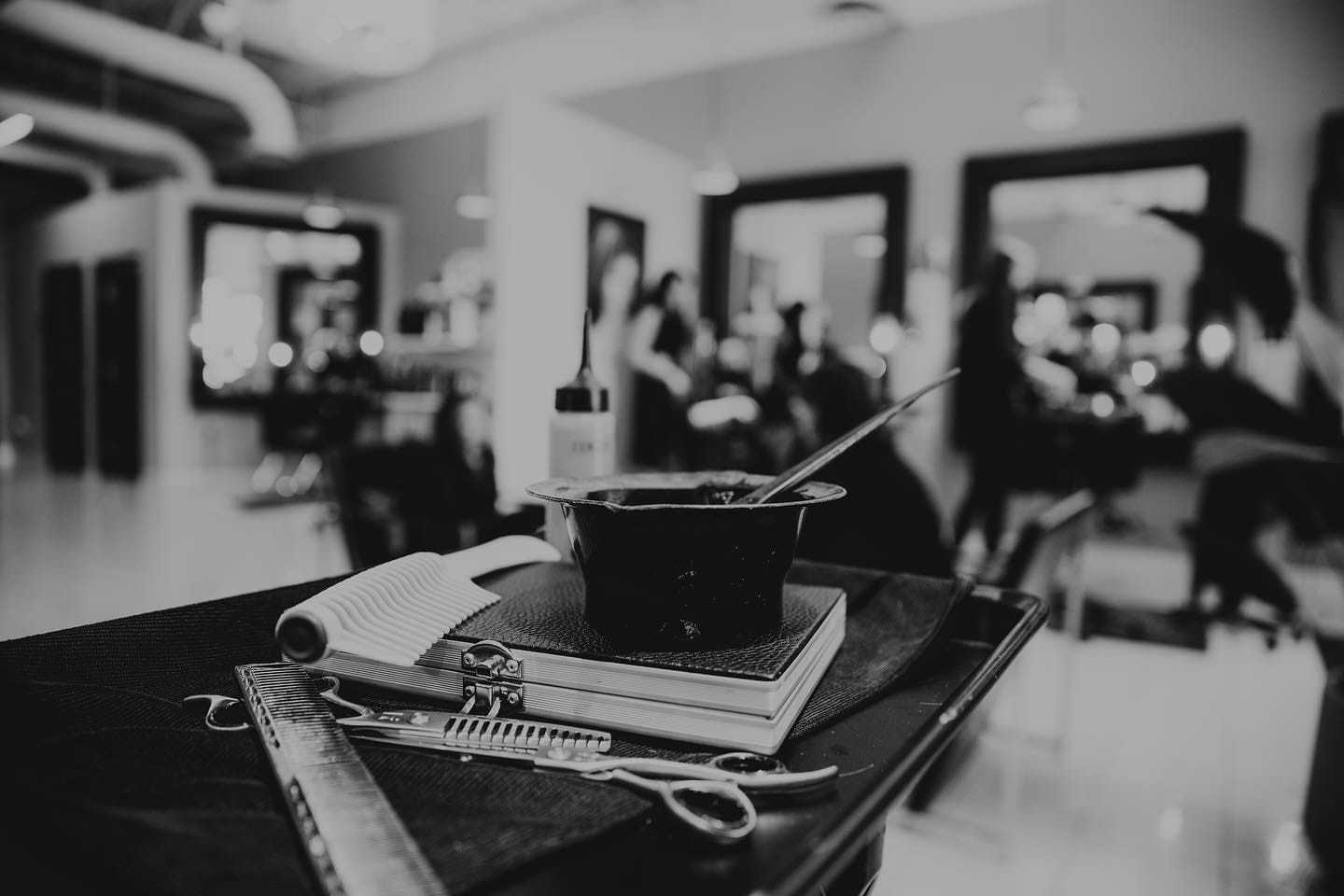 Black and white photo of hair salon tools on a table with blurred background.
